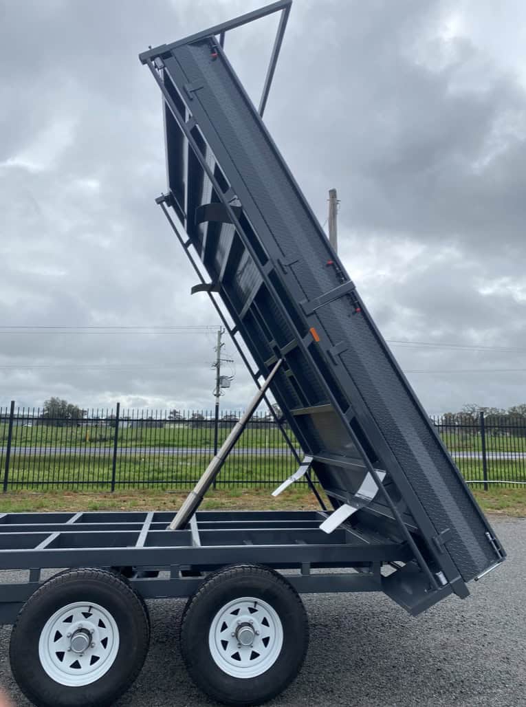 Tipper trailer with raised flatbed on cloudy day.